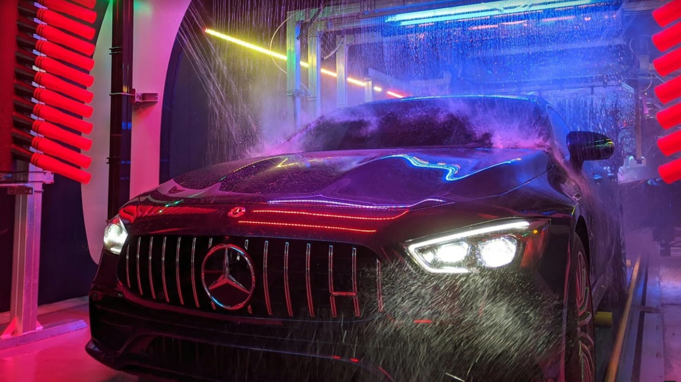 A car mid-rinse under full-spectrum neon lighting